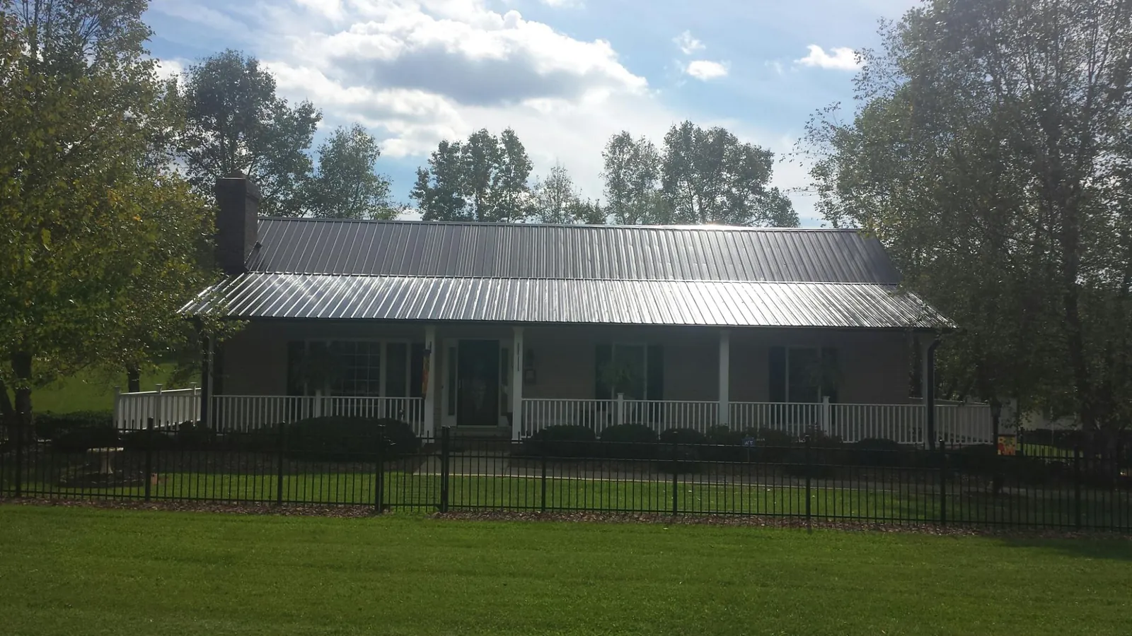 Gray metal roof on a brick ranch with a full width front porch — Gutter Guard Installation work by our crew in Grant